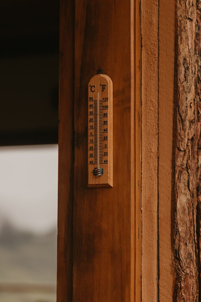 get-in-touch A wooden wall with a vintage thermometer displaying temperature in Celsius and Fahrenheit.