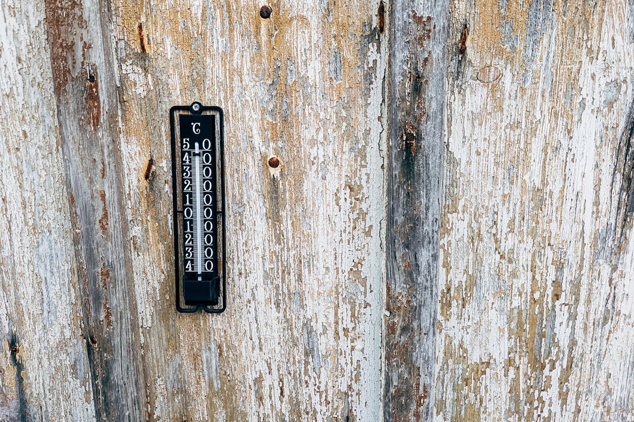 A vintage thermometer mounted on a rustic wooden wall. Perfect for themes of nostalgia and weather monitoring.