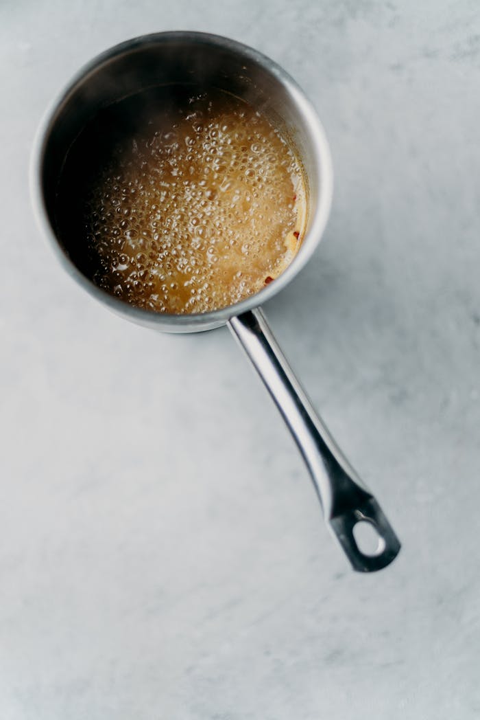A high-angle view of simmering soup in a stainless steel saucepan, showcasing food preparation.